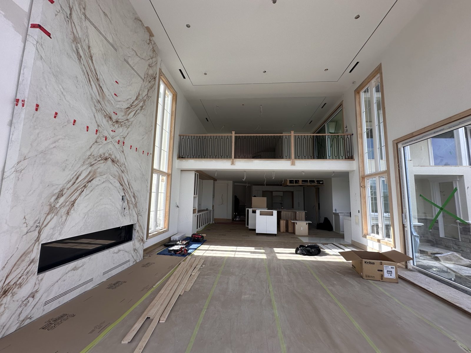 Double-height great room with a book-matched stone feature wall and linear fireplace at the Fenton Way residence, Brampton